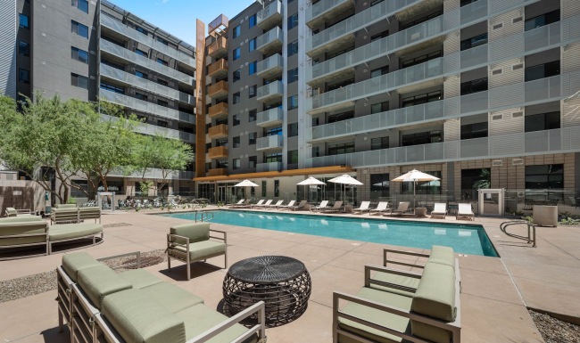 Pool and patio with beach chairs and umbrellas in the shared courtyard at Adara apartments in Downtown Phoenix, AZ. 